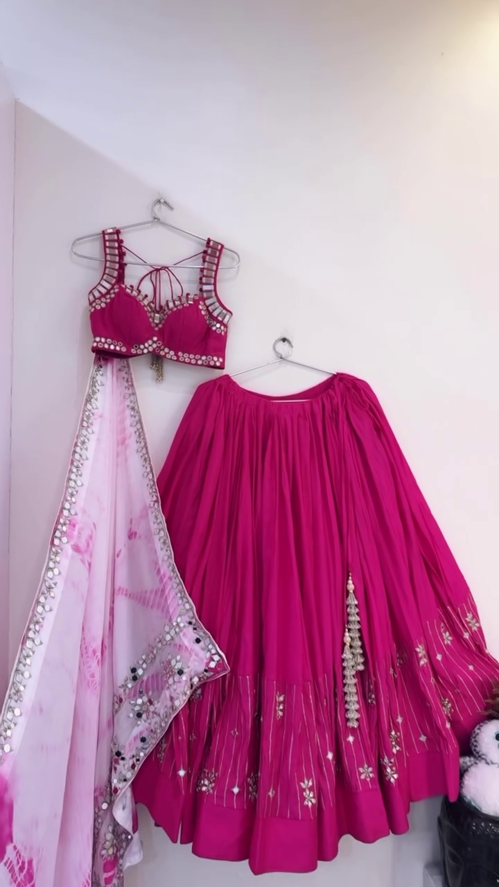 Rani Pink Mirror Work Lehenga Choli Set Featuring a Sleeveless Embellished Blouse with Tie-Up Back, Paired with a Flared Embroidered Lehenga and Soft Tie-Dye Dupatta with Mirror Border – Ideal for Mehendi, Haldi, or Festive Celebrations